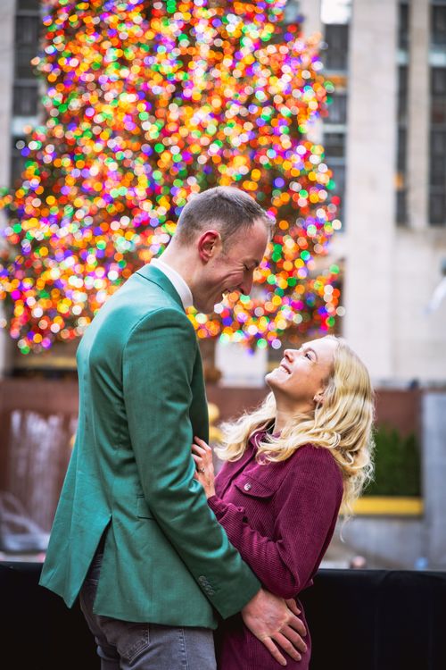 couple posing in front of the The Rockefeller Center Christmas Tree during holidays in New York City 