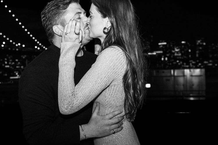 guy kissing a girl by the Manhattan bridge with big engagement ring 