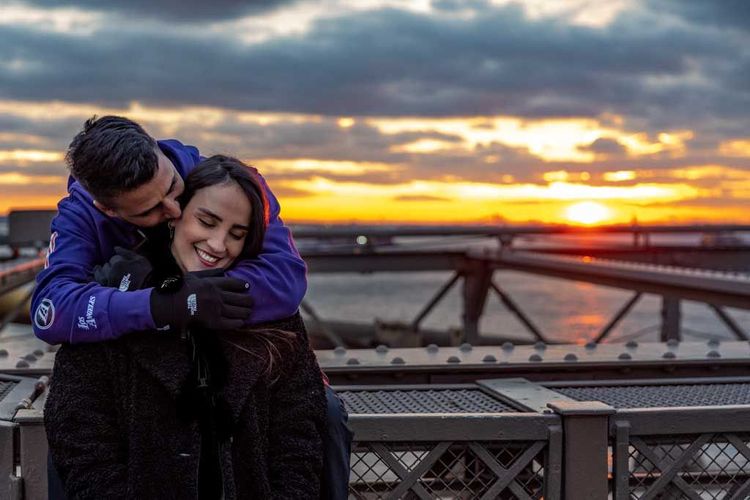 guy kissing girl on Brooklyn Bridge during sunset 