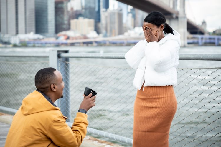 black guy holding engagement ring in dumbo by the Brooklyn Bridge 