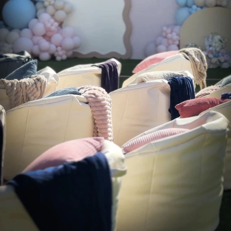 White bean bags with pink and navy throws in front of a pastel balloon backdrop