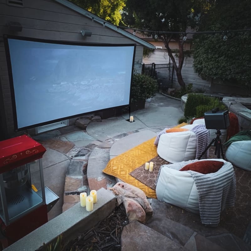 Patio movie screen with bean bags, layered rugs, candles, and a popcorn machine