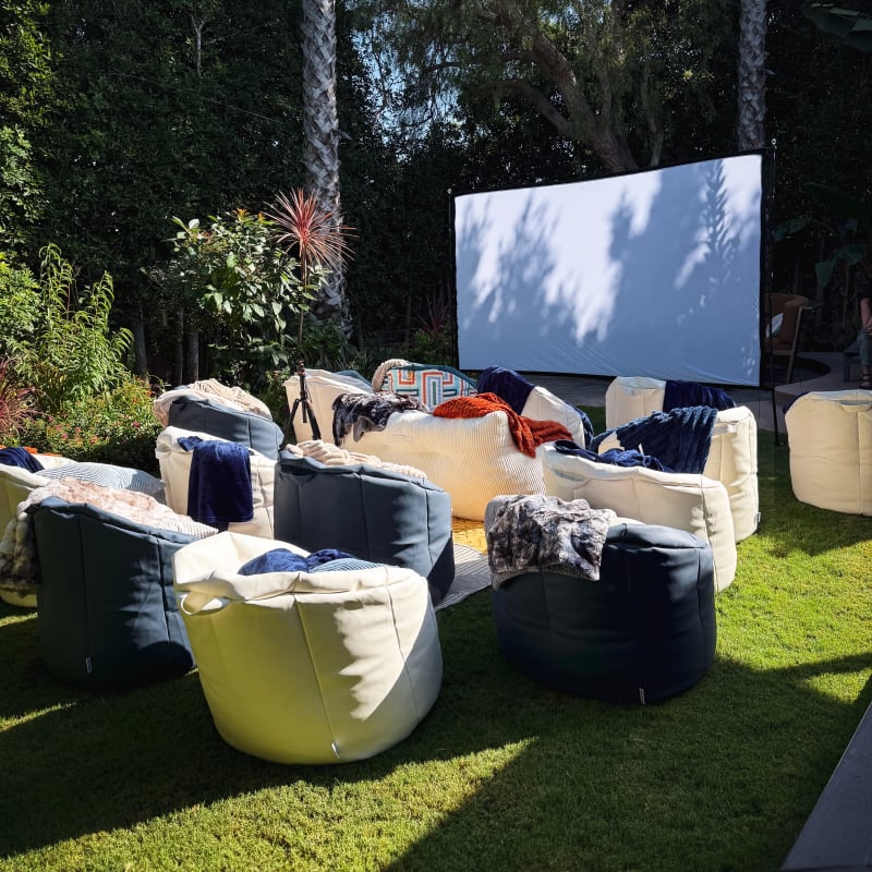 White and blue bean bags arranged on a garden lawn facing an outdoor movie screen