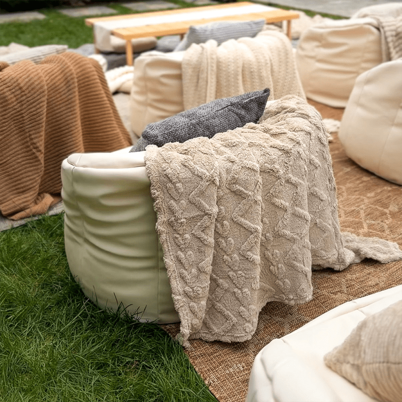 White bean bags with cream and caramel throws arranged on rugs beside a low wooden table