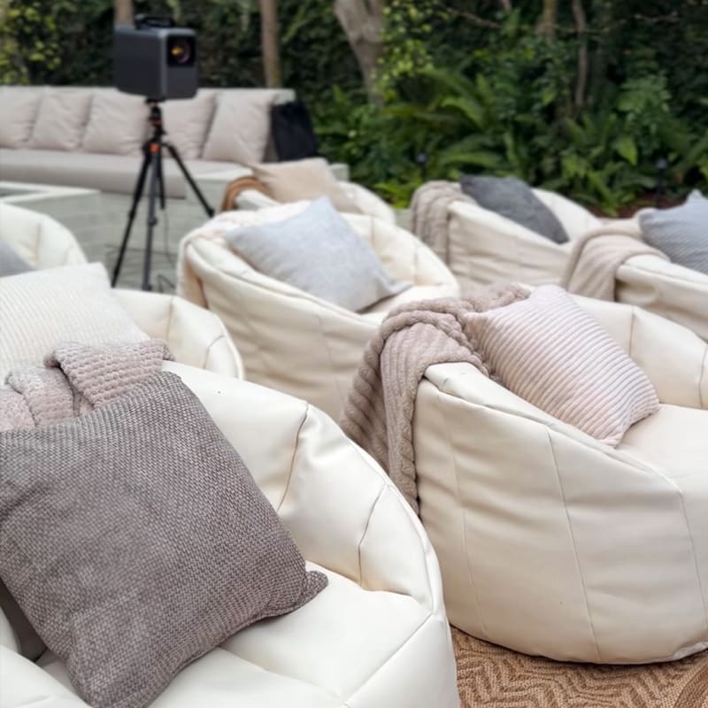 White bean bags with neutral cushions and knitted throws beside an outdoor projector