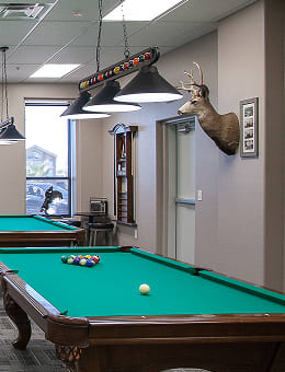 Cozy billiards room with pool tables and mounted deer on the wall. Recreational space for active adults in Goodyear, AZ.