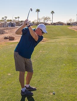 Active senior man ready to swing at the Cotton Lane RV Resort golf course in Goodyear, AZ.
