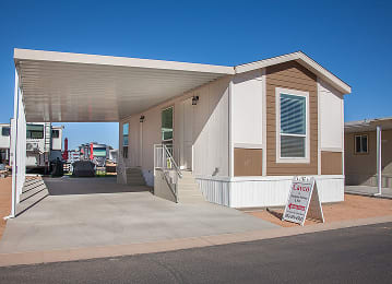 Exterior view of a manufactured home with a double slide door entrance at Cotton Lane RV Resort.