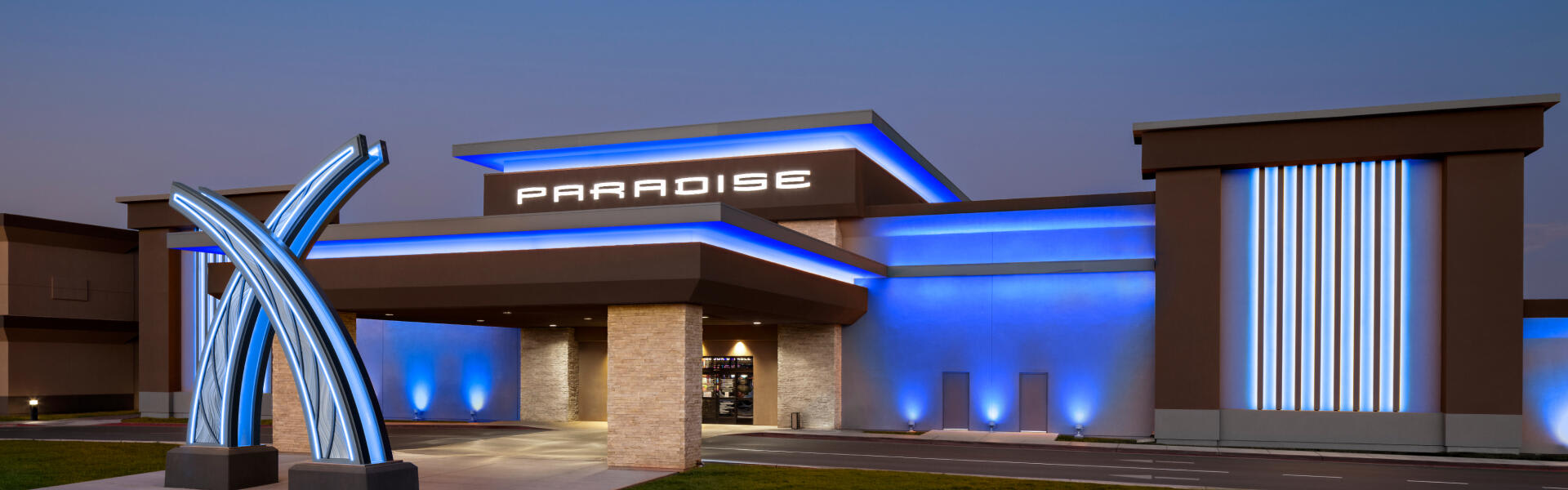 Paradise casino front entrance at dusk with blue accent lights.