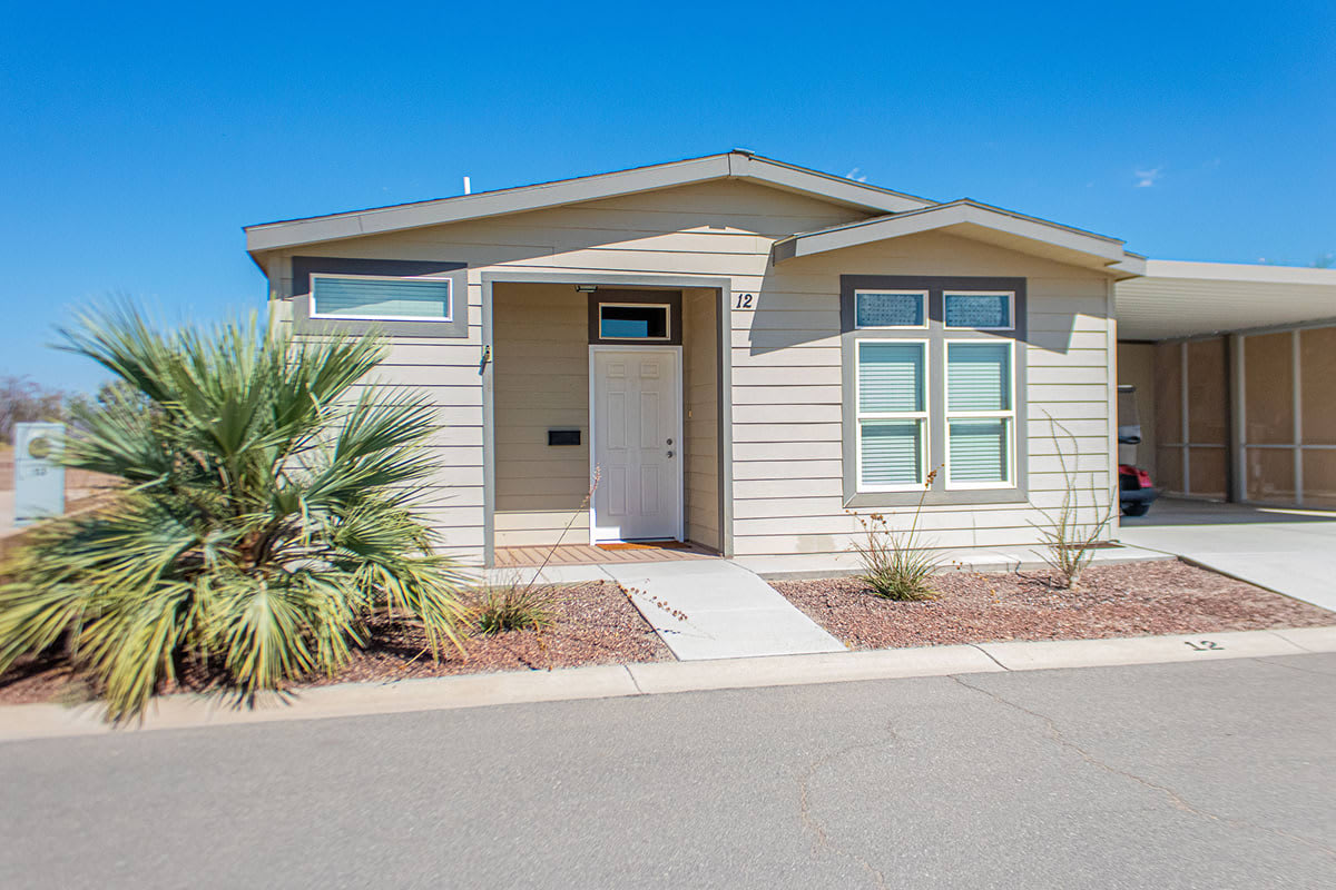 Cream sided manufactured home with a gabled porch, fan palm and gravel desert landscaping