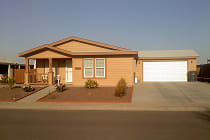 Tan manufactured home with a covered porch and an attached two car garage