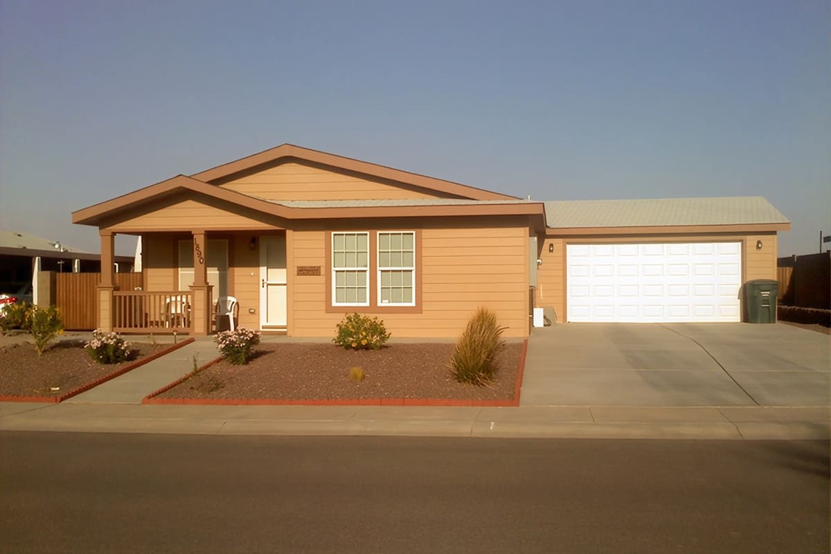 Tan manufactured home with a covered porch and an attached two car garage