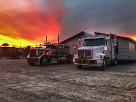 Wide load trucks at sunset during home transport