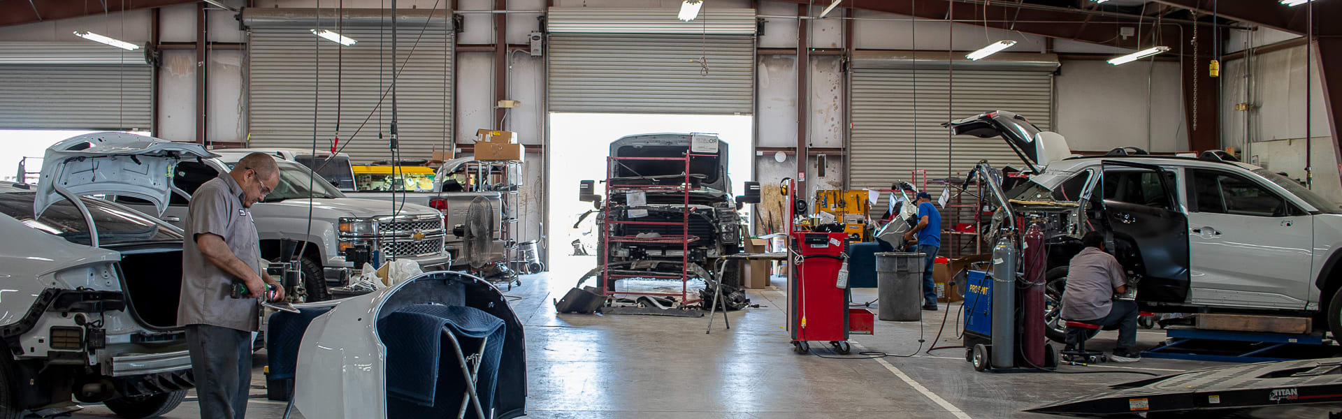 A view inside the main work bay at Smitty's with a worker making adjustments to the rear of a car.