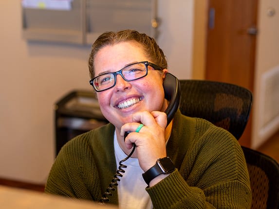 A smiling employee answering the phone at our front desk.