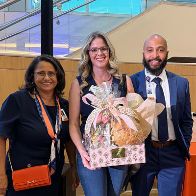 Three Yuma County Chamber members smiling together at a Chamber event, one holding a gift basket