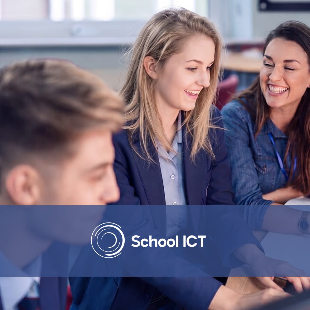 Female teacher smiling and talking with secondary school students working on a computer.