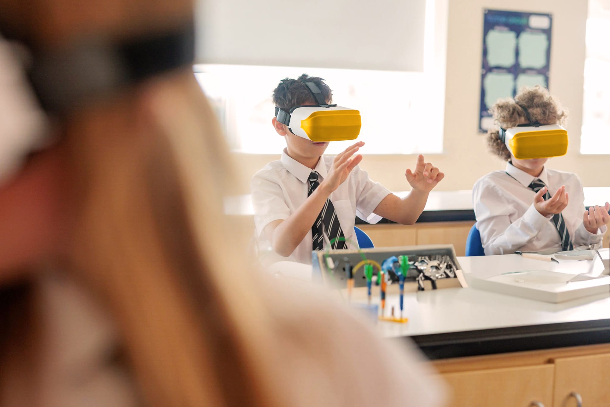 Two pupils wearing virtual reality headsets during a lesson at a classroom science bench