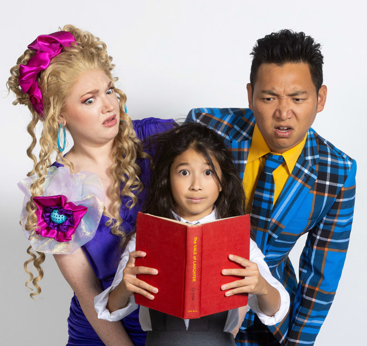 Mr. and Mrs. Wormwood stand over Matilda perplexed by the book that she is holding.