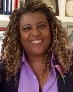 Dee Spencer a black woman with blonde braids in curls wearing a purple shirt and smiling