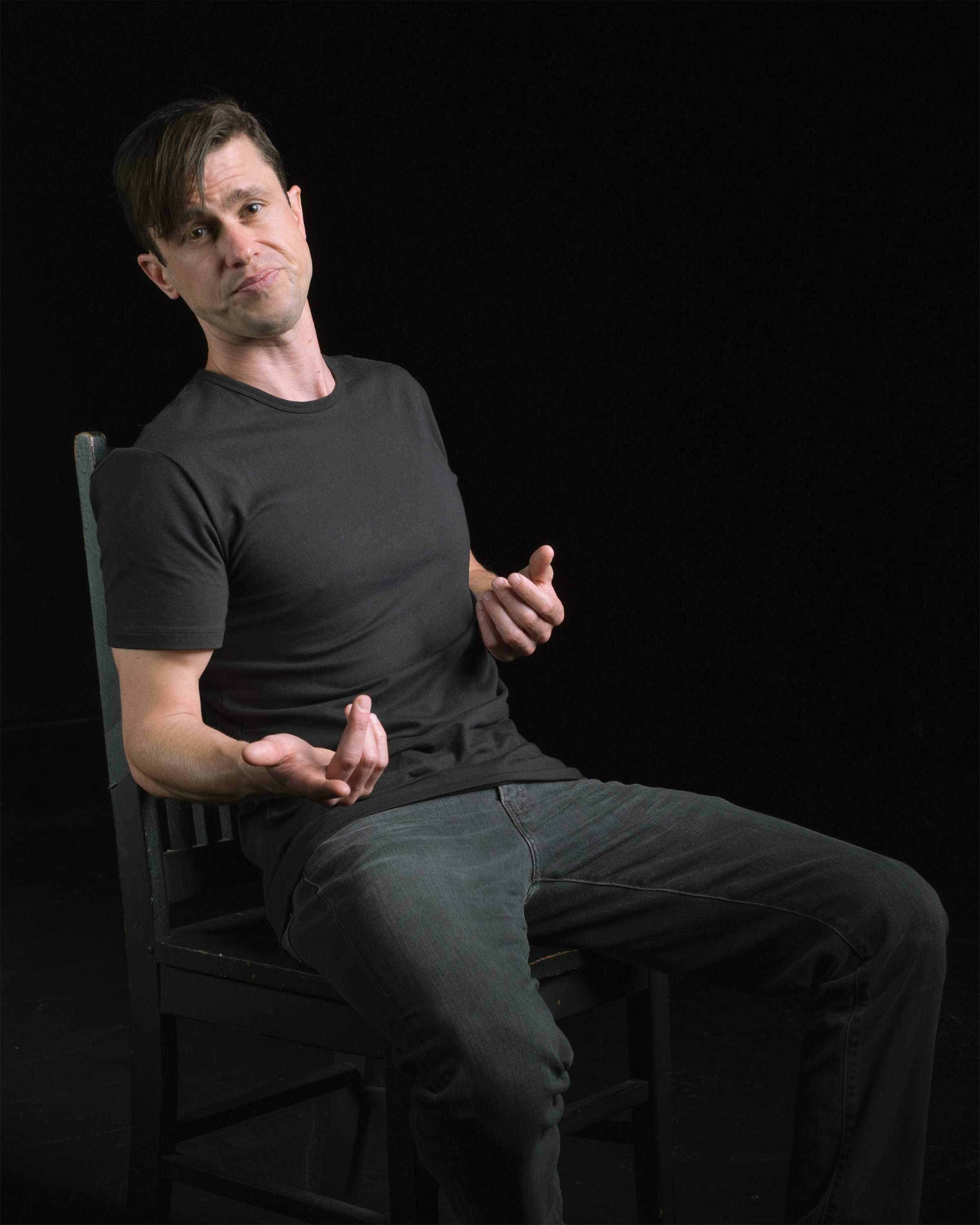 Dan Hoyle in a gray t-shirt sitting down.