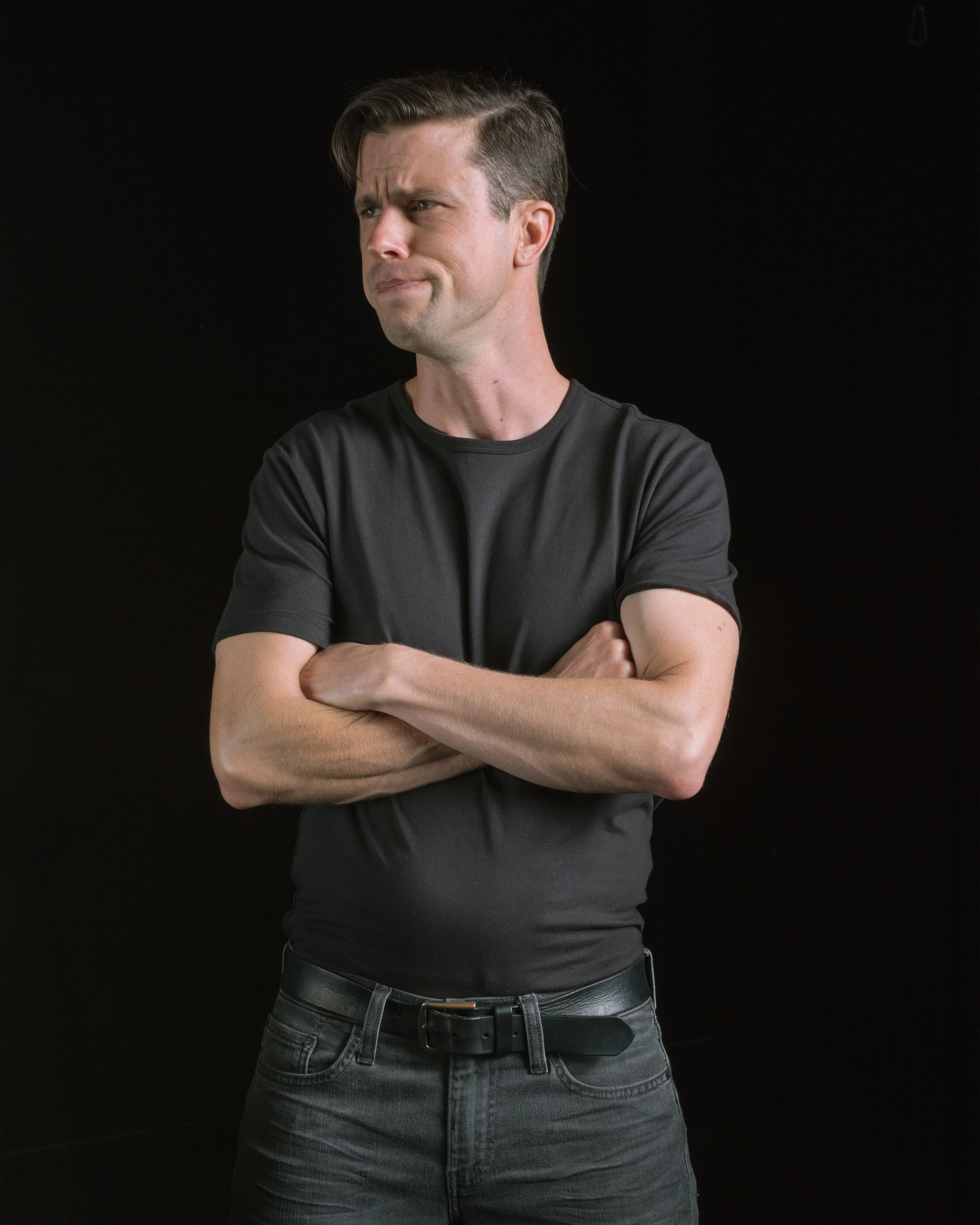 Dan Hoyle in a gray t-shirt with arms crossed.