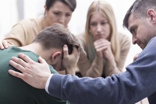 A sad man being comforted by co-workers