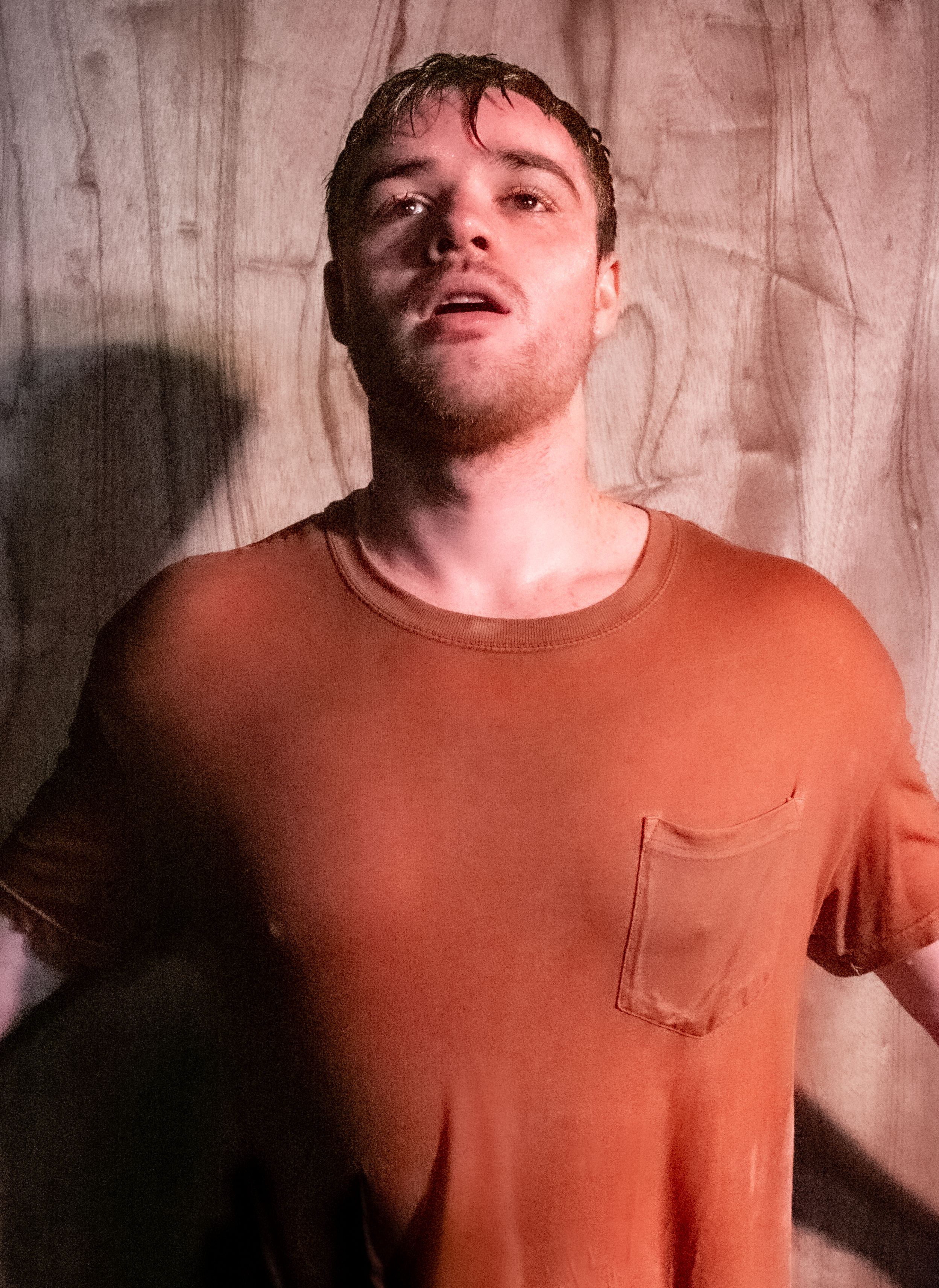 One actor in an orange shirt, looking up