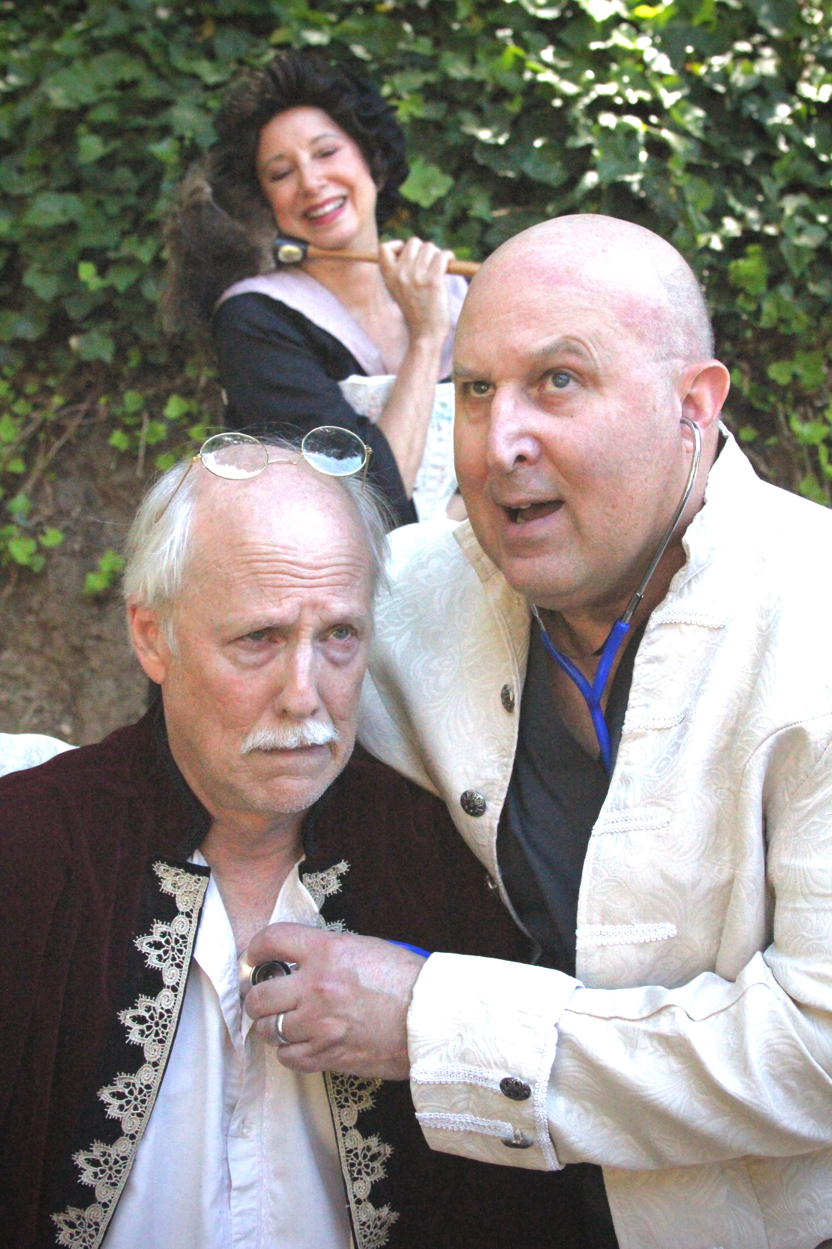 Doctor Purgeon (David Ghilardi) examines Argan (Bruce Kaplan) while Toinette (Kim Saunders) looks on with concern