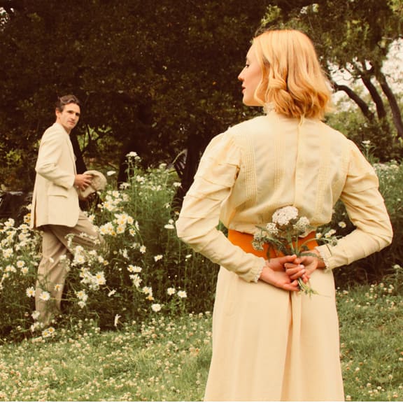 Lucy (Sophie Ruf) and George (Tyler Scott Null) meeting one another in a field of flowers.