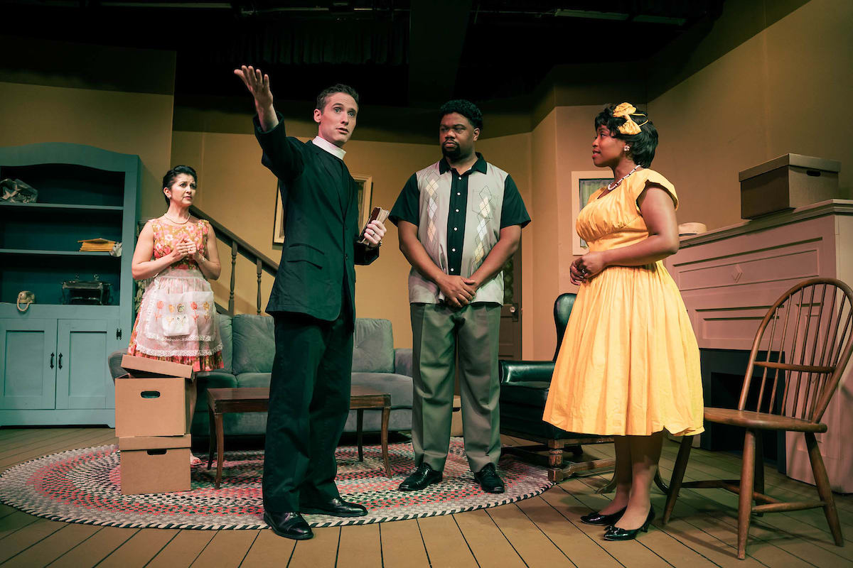 Photo shows a priest discussing something with a couple