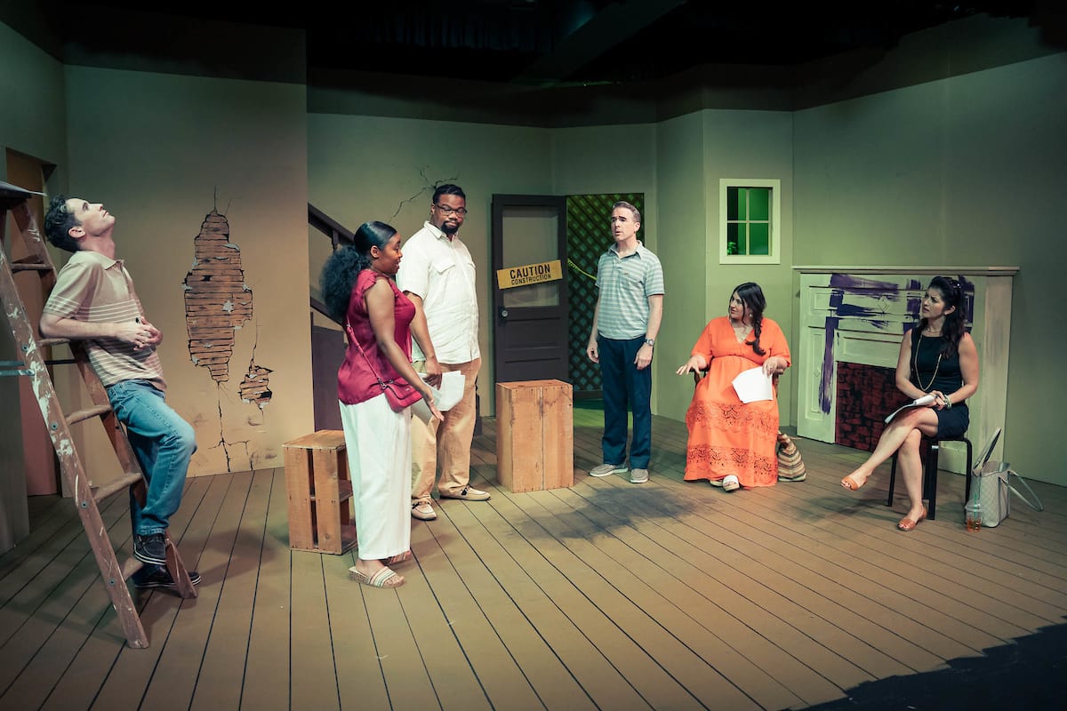 Photo shows a groups of people having a meeting in a rundown house