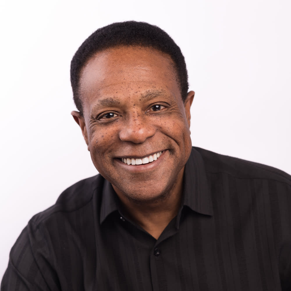 A square headshot of a Black male-presenting actor smiling into the camera.