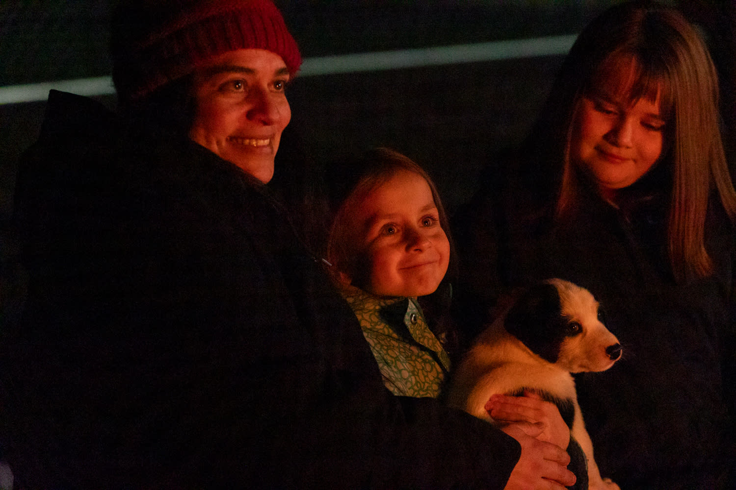 A family with a puppy enjoying the glow of a fire