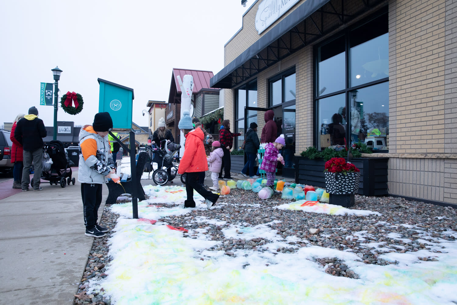 Kids enjoying vibrantly colored snow and ice blocks outside of a local storefront