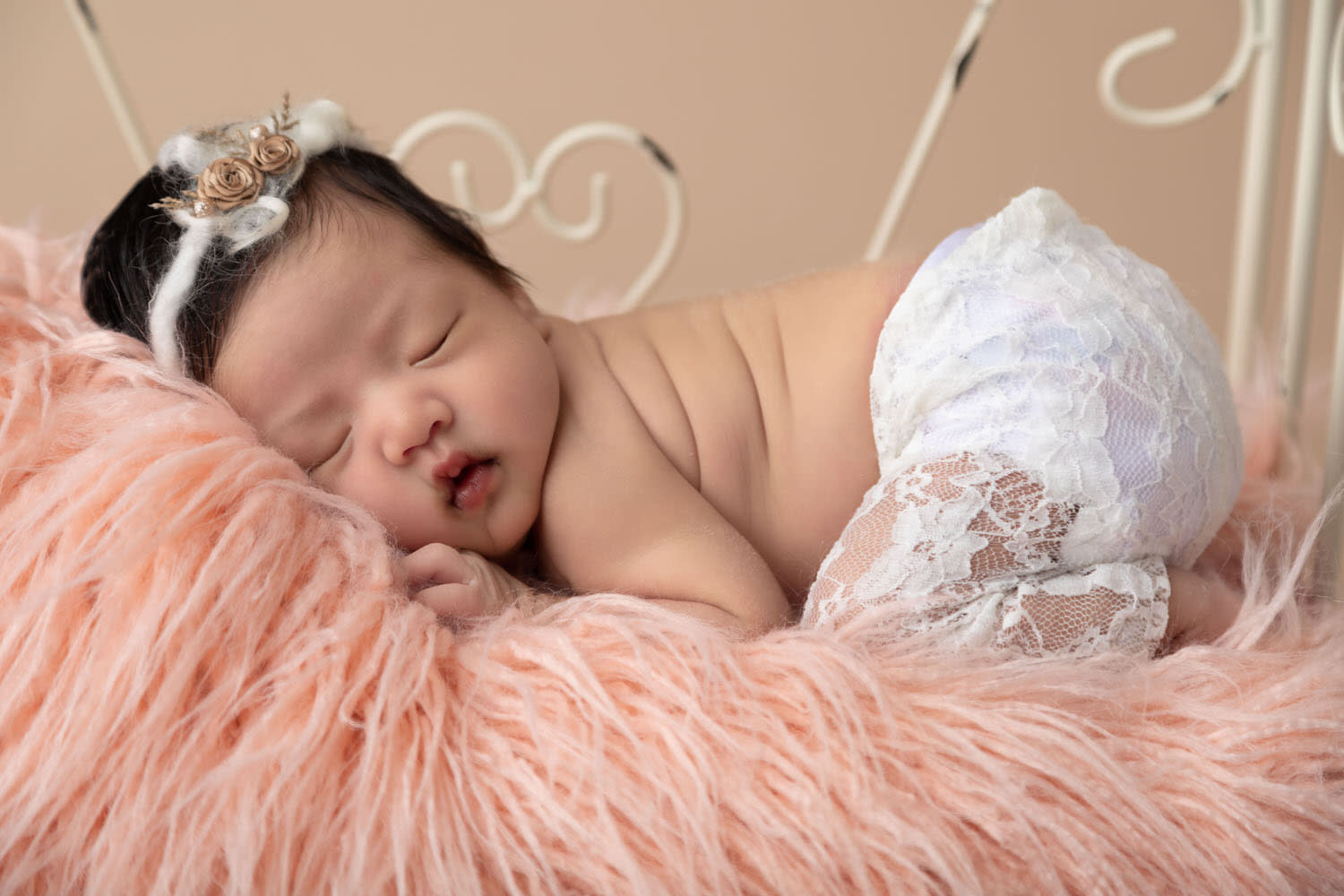 Newborn girl portrait. Lace pants,  White wire bed. Pink flokati