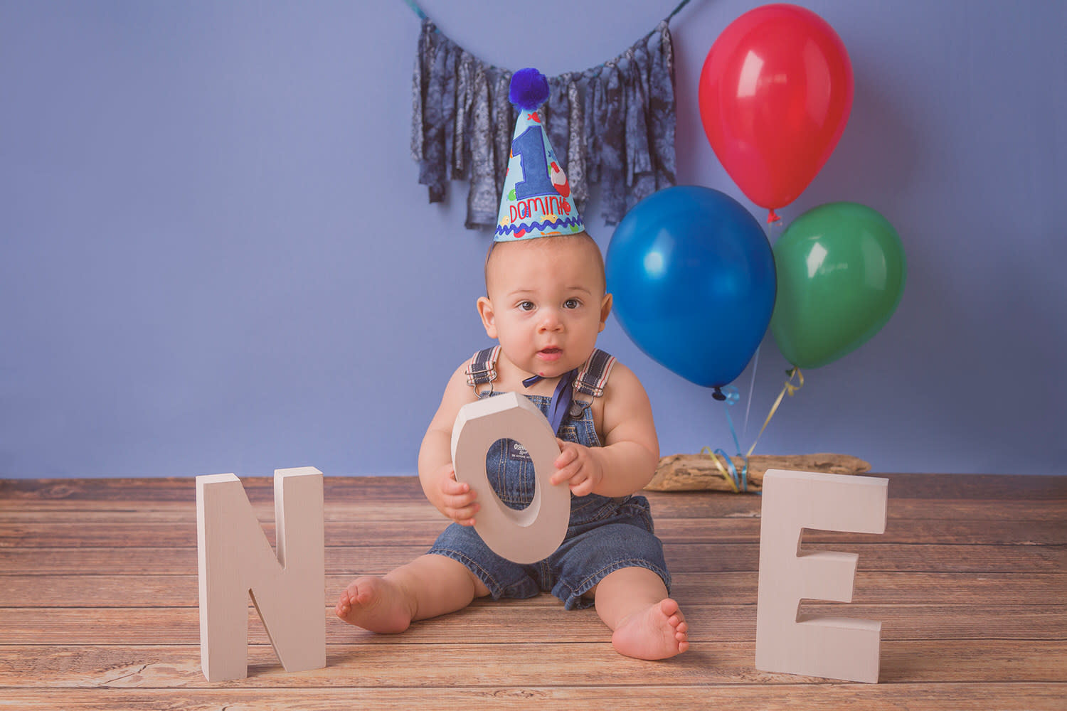 Boy First B Day Portrait. Denim Overalls. Cone Cap