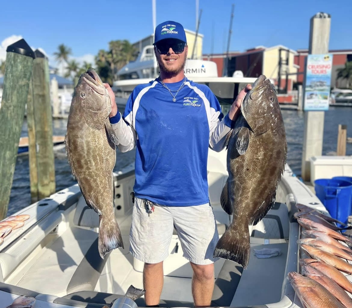 Captain holding two big fish in both hands with a big smile