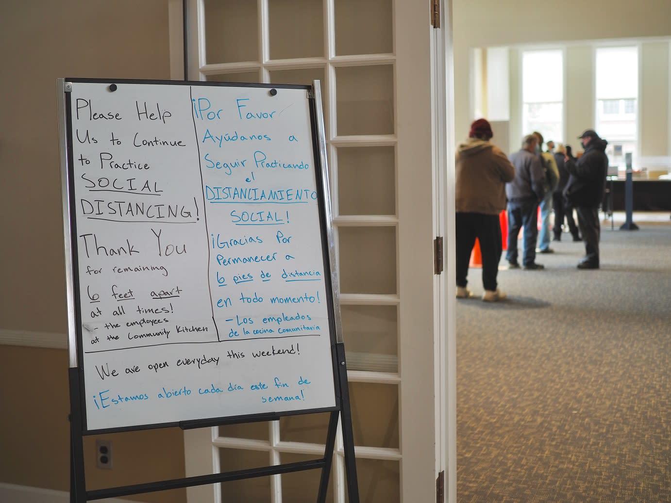 Entrance of the Community Kitchen, featuring a sign reminding guests to practice social distancing at all times.