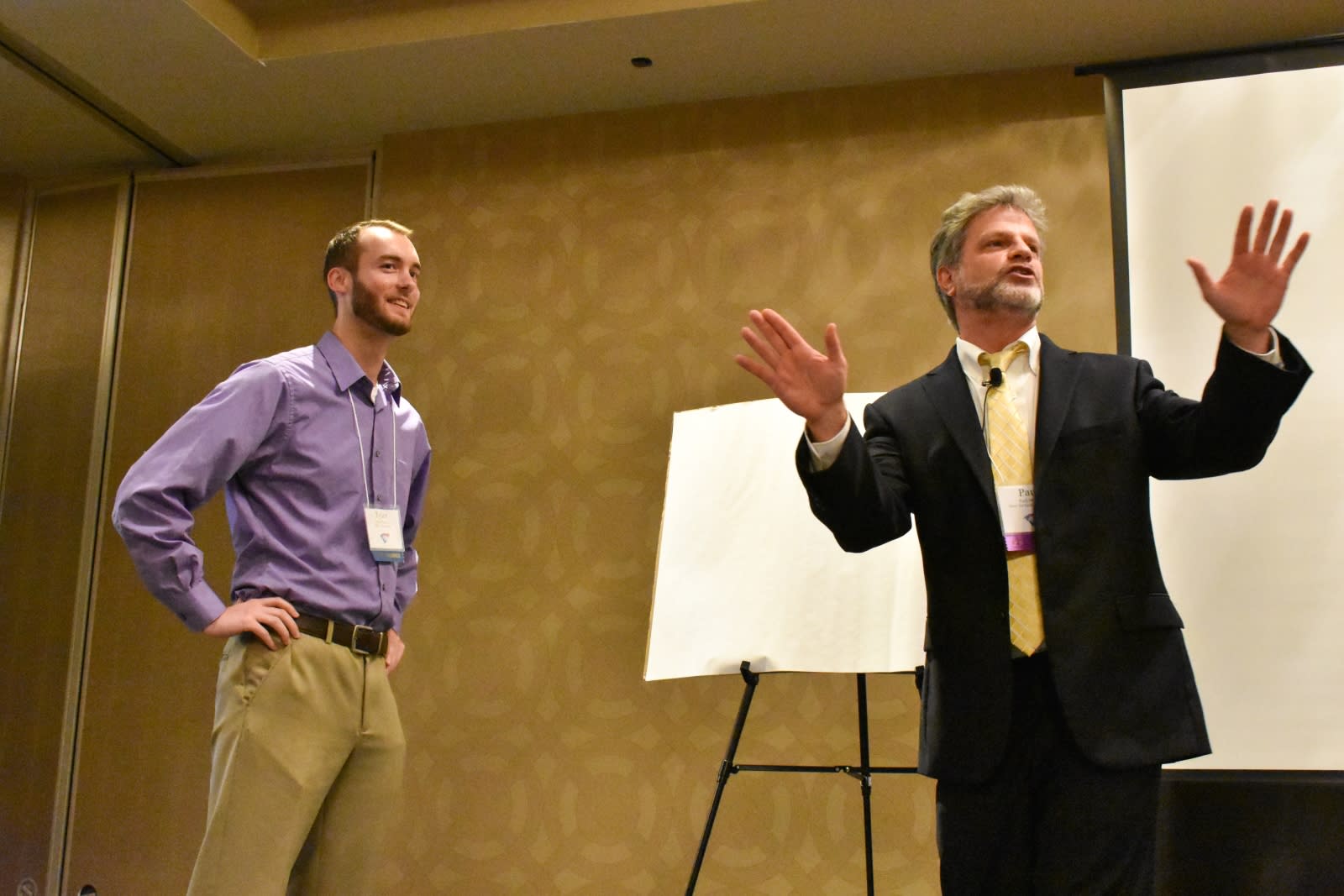 Paul expressing his hands to the audience while on stage with a guest at the event