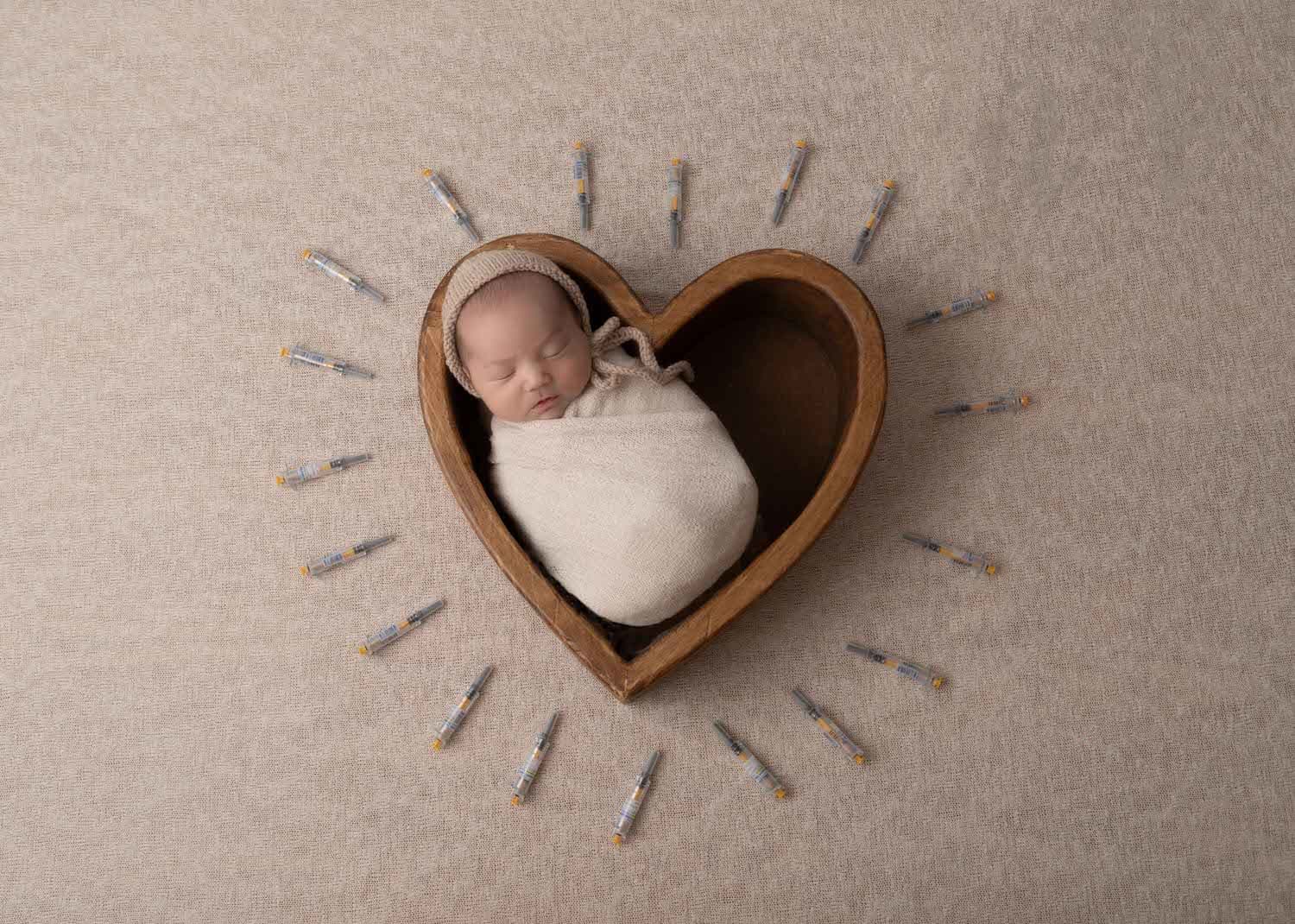 Newborn Boy In Heart Shaped Bowl surrounded by IVF Needles
