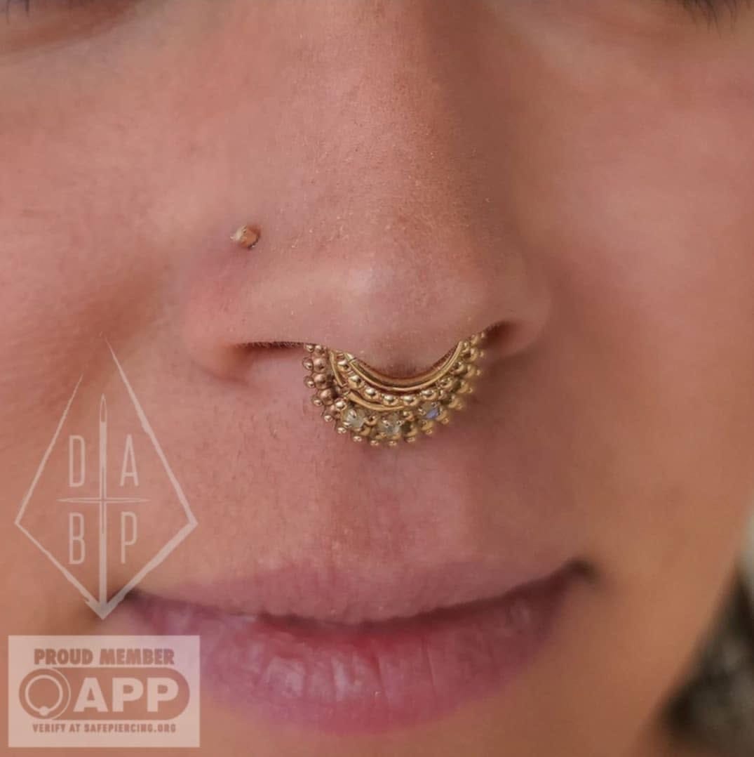 A healed septum piercing with multiple gold rings stacked in it