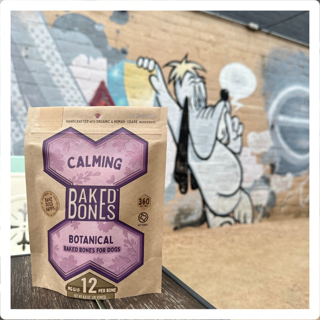 Bag of Calming BakedBones in the foreground with a graffiti drawing of Droopy Dog on a wall in the distance