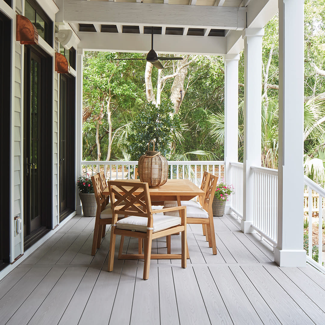 wooden table and chairs on a covered porch surrounded by trees
