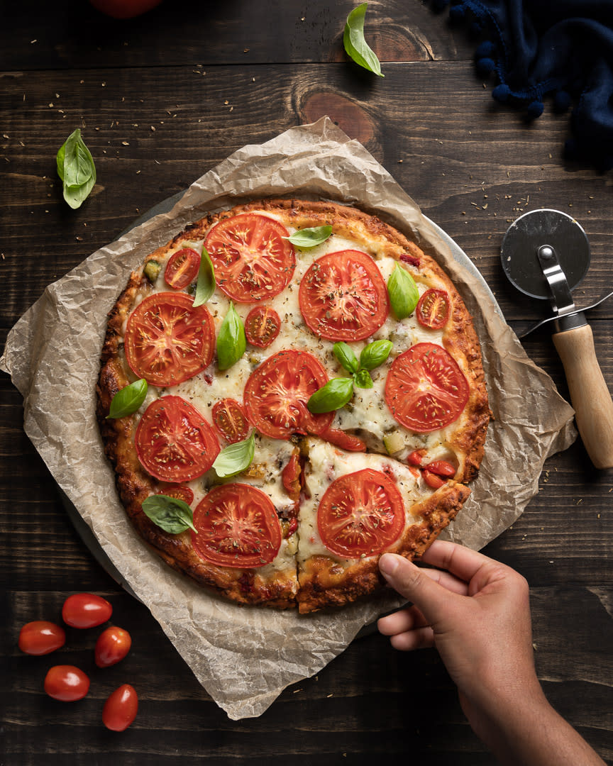 Food photography of margarita pizza, tomato, cherry tomatoes, cheese, basil leaves on a rustic background