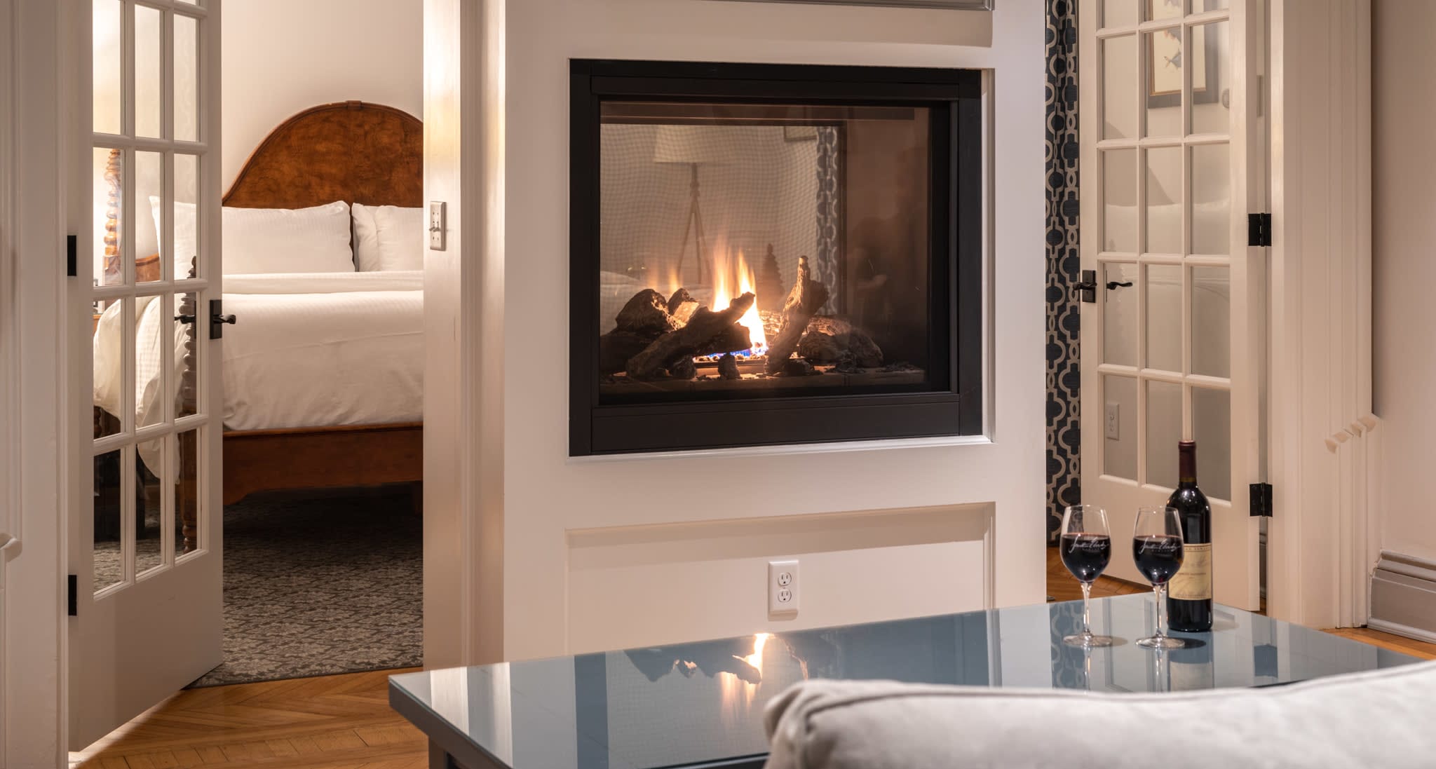Hotel double-sided gas-lit fireplace and wine glasses on table in Downtown Mystic