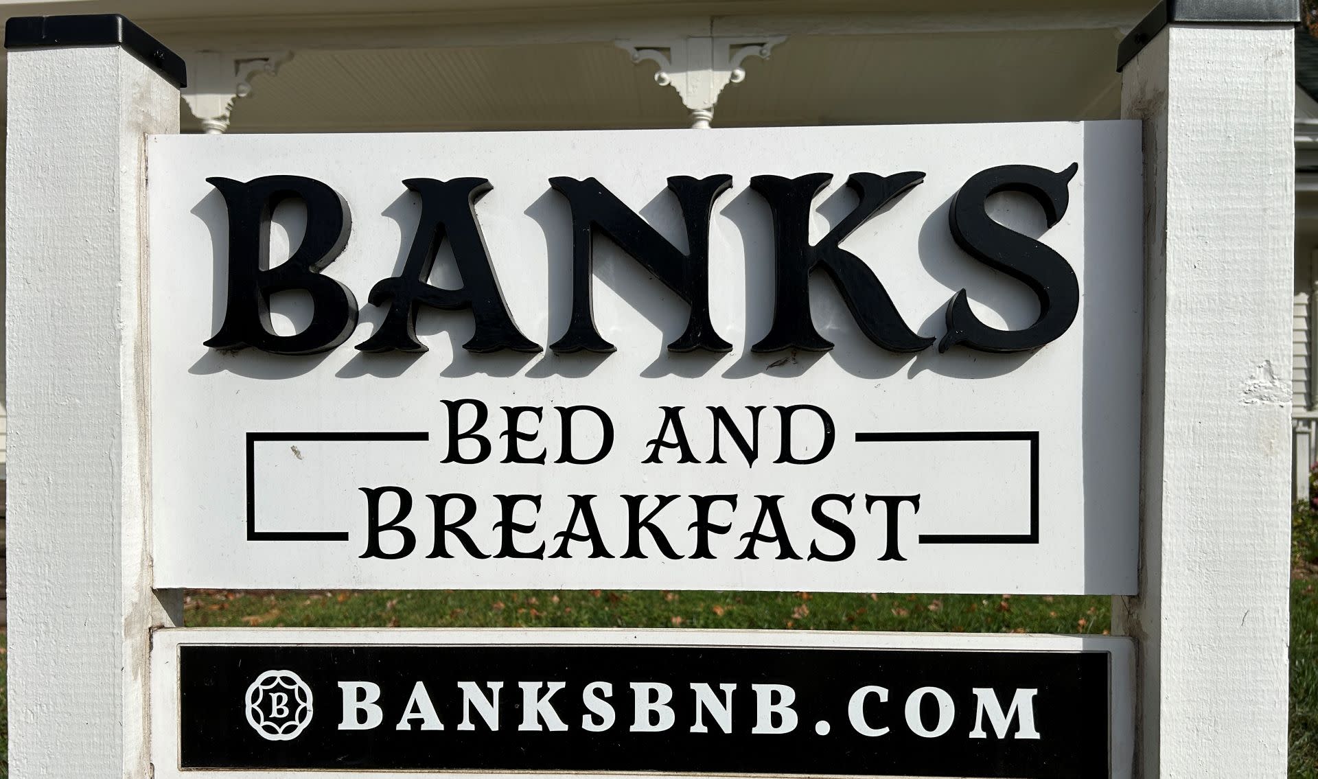 White sign with black text that says, Banks Bed and Breakfast on top and black sign with white letters that says banksbnb.com