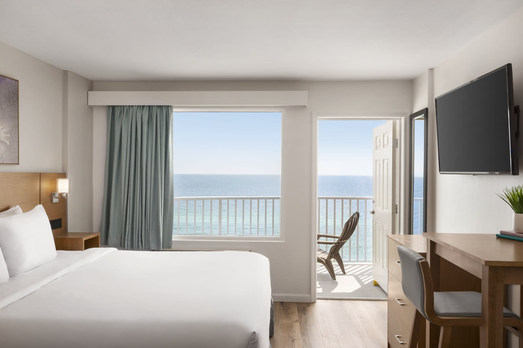 hotel room with door open to balcony overlooking the beach