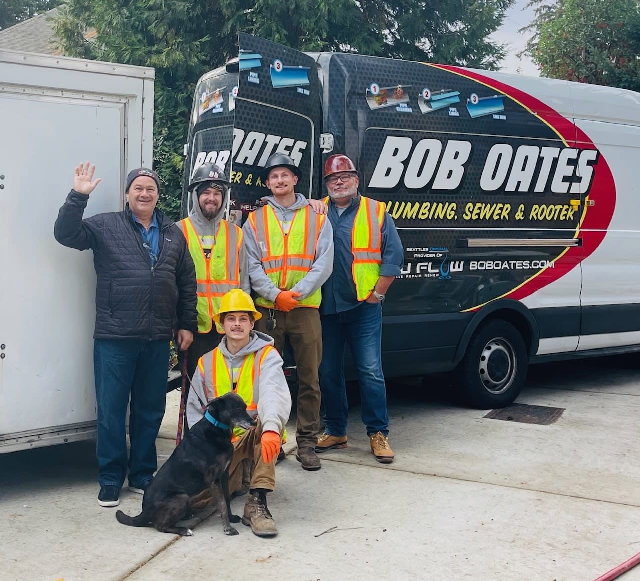 Bob Oates and team members in front of company trucks, waving