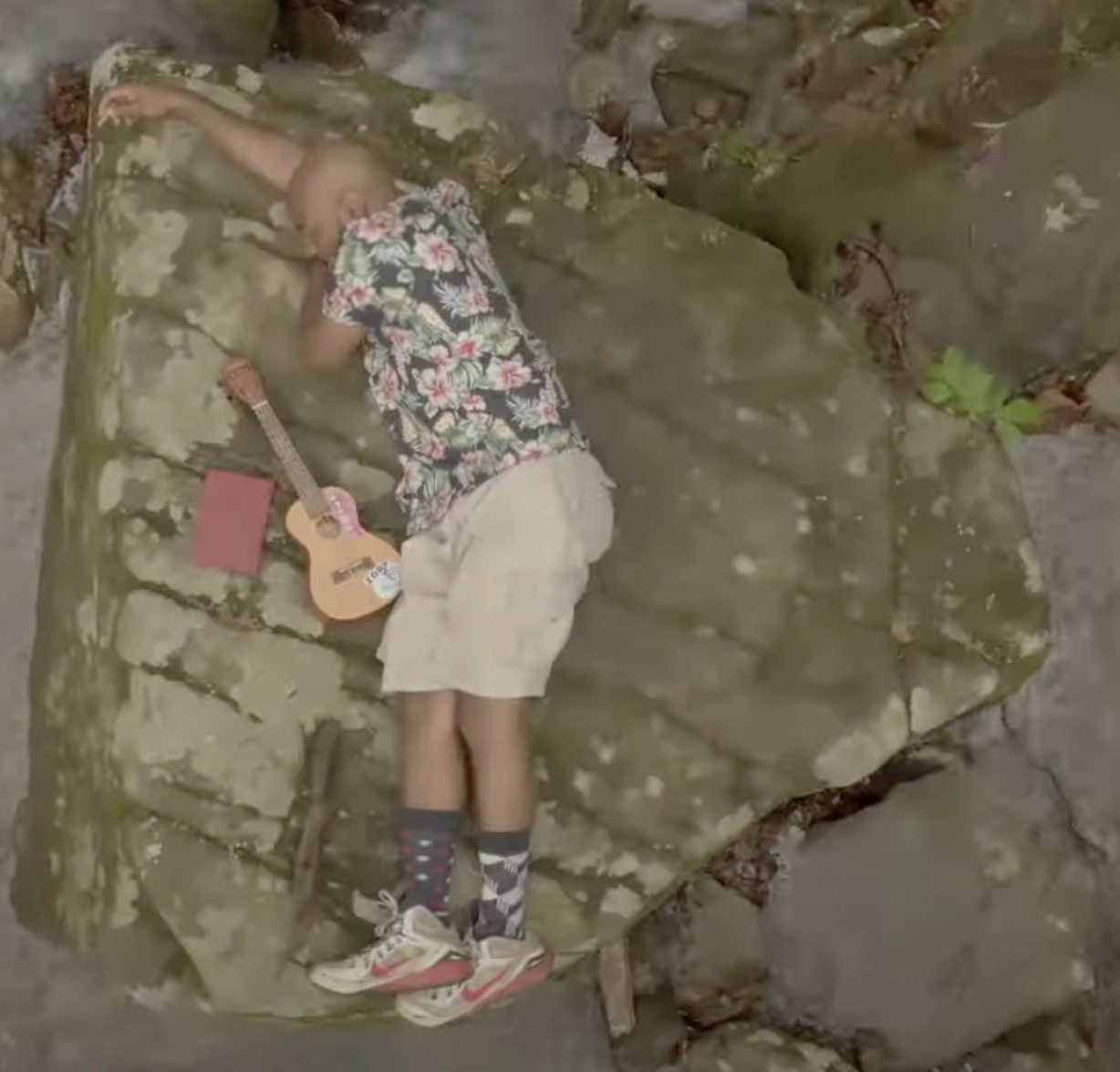 Austin Ashford lying on a rock next to ukelele and notebook